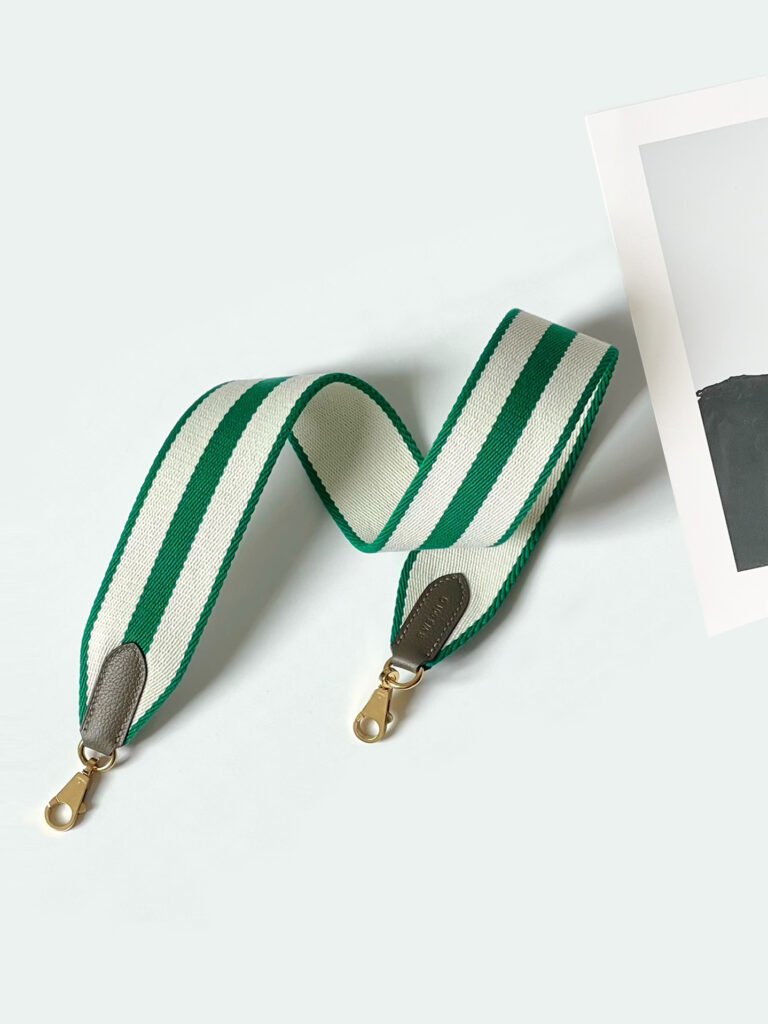 A wide 50mm canvas shoulder strap with smooth leather trim and equestrian-inspired hardware, shown attached to a handbag as a stylish crossbody replacement.