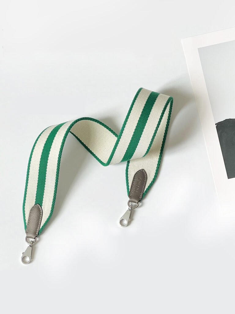 A wide 50mm canvas shoulder strap with smooth leather trim and equestrian-inspired hardware, shown attached to a handbag as a stylish crossbody replacement.